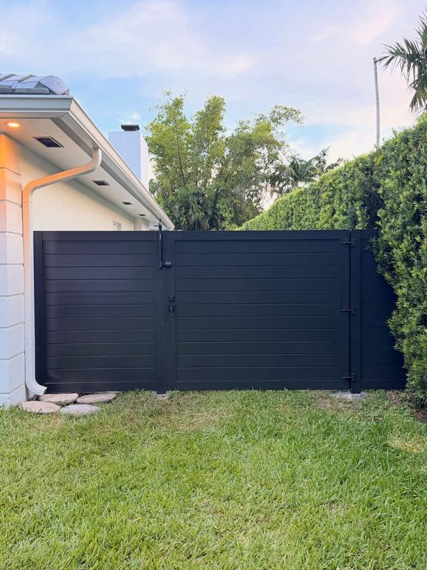 Black horizontal slat double gate between house and hedge