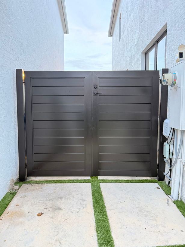 Dark bronze horizontal slat double side gate between white stucco walls