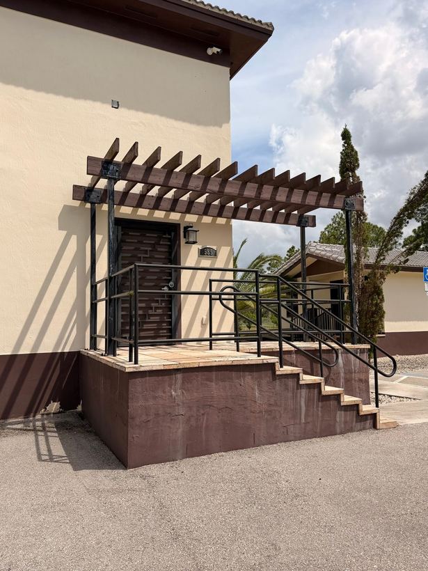 Steel entry landing railings and stair handrail under a wood pergola