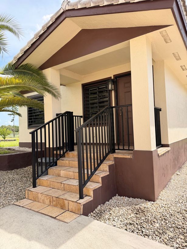 Black railings on the paver entry steps of a residential porch