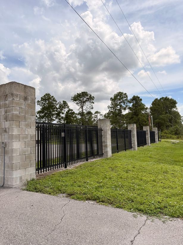 Black spear-top picket fence panels between masonry block columns
