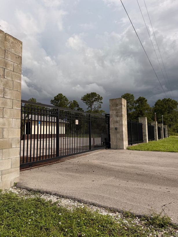 Large black sliding entry gate between masonry block columns